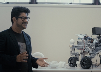 Dr Eduardo Benitez Sandoval beside a four-wheeled robot used in the Creative Robotics LabE